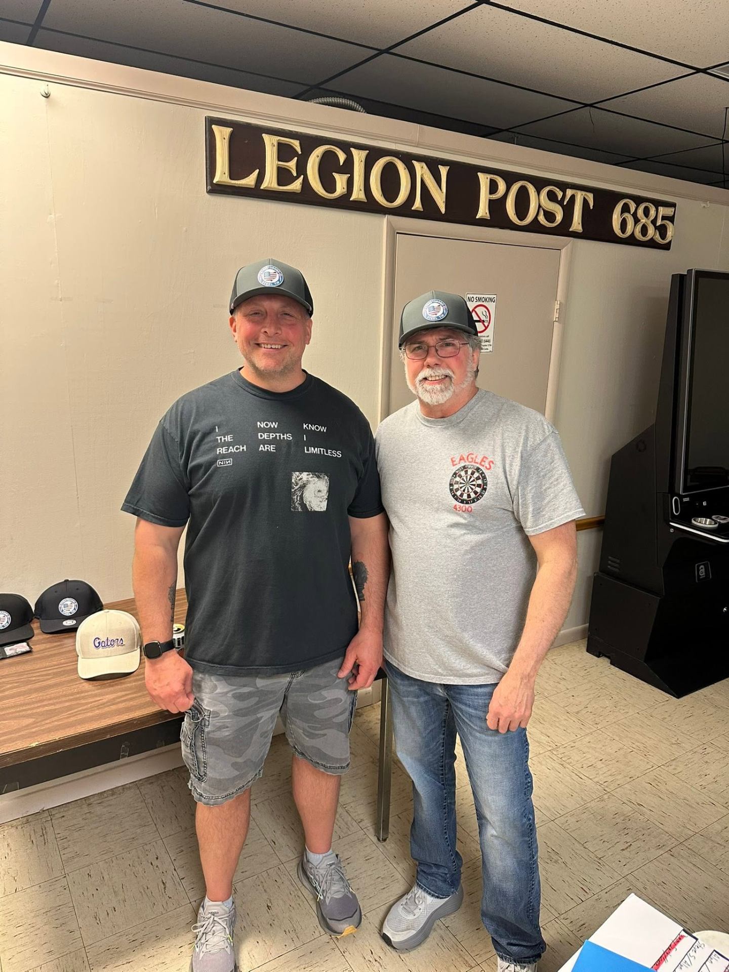 Steve Suprenant and Alan Stiftar wearing newly won Streetsboro Steel Tip hats under the Legion Post 685 sign